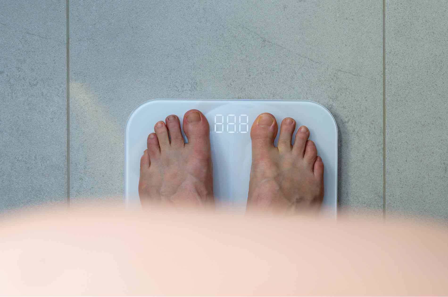 Uomo si pesa sulla bilancia